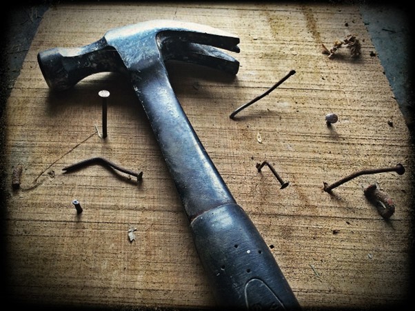 renovating your home in summer, an unsplash image,  a hammer and nails on a wooden board