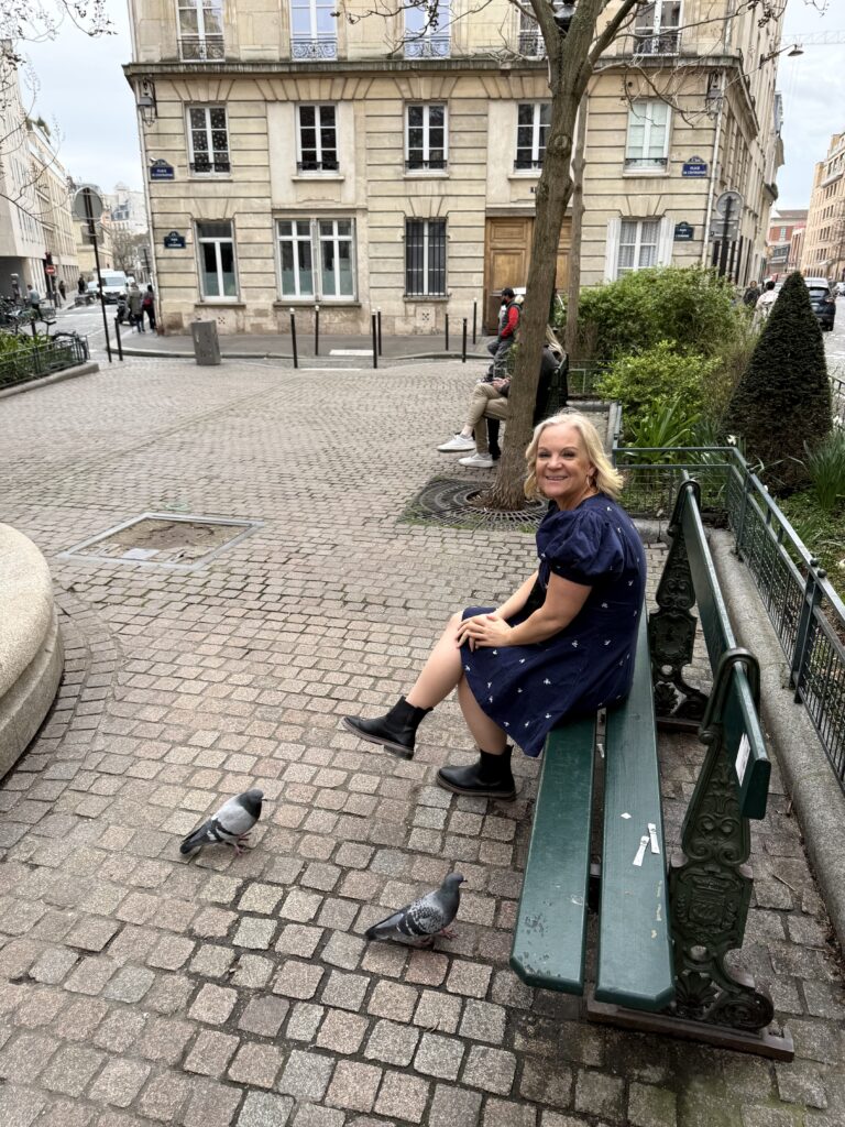 Blogger sitting on a green bench in the filming location from emily in  Paris 
