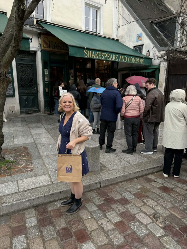 Issy from A Suffolk Mum holding a Shakespeare and Company bag outside the iconic Paris bookshop